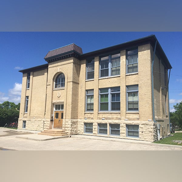 One of the buildings where the Canadian Centre for Child Protection operates: a two-storey early 20th century brick building with tall windows and a few steps leading up to double wooden doors.